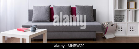 Geräumiges Wohnzimmer mit Couch und Kissen. Neben dem kleinen hölzernen Couchtisch Stockfoto