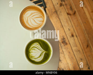 Zwei Tassen Matcha Tee und Cappuccino mit schönen latte Kunst auf grauen Farbe Tabelle. Stockfoto