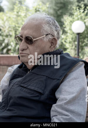 Älterer Mann mit Sonnenbrille Sitzen im Freien, in der Nähe Stockfoto