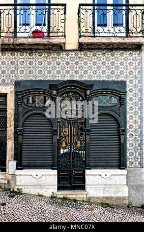 Fassade des Townhouse in Martim Moniz mit verzierten schwarzen Tür mit gold Dekoration, durch keramische Fliesen- Mauer umgeben Stockfoto