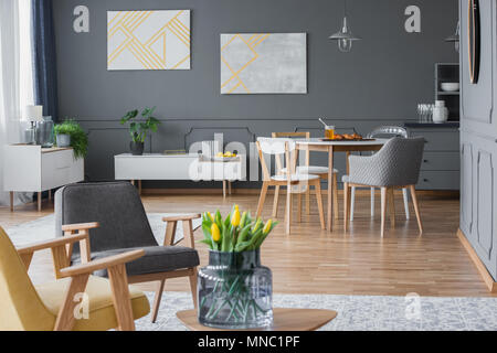 Glas Vase mit gelben Tulpen in einem Wohnzimmer mit Essbereich Stockfoto