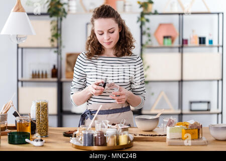 Verkäuferin der natürlichen Produkte eine lösen Glas Glas für organische Creme Stockfoto