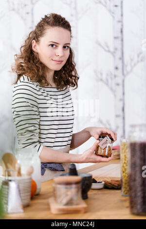 Lächelnd selbst - Frau Verpackung bio Produkte im Glas beschäftigt Stockfoto