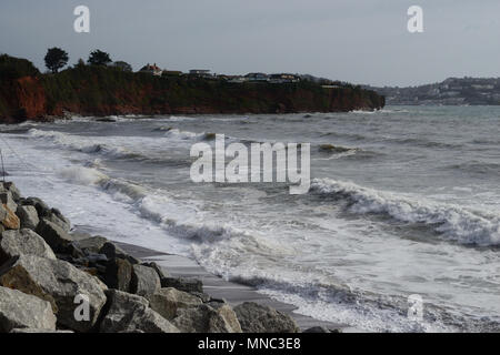 Rock Rüstung schützen die Basis des roten Sandsteinfelsen aus der rauen See am Hollicombe Beach. Stockfoto