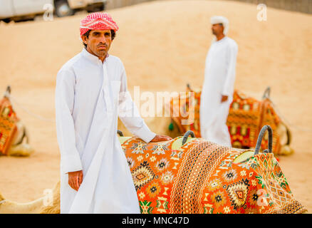 Arabischer Mann in der Nähe von Kamelen in der Wüste Stockfoto