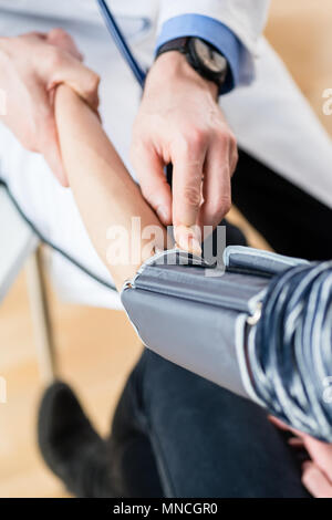 Hand eines Arztes, der die Messung der Blutdruck eines Patienten Stockfoto