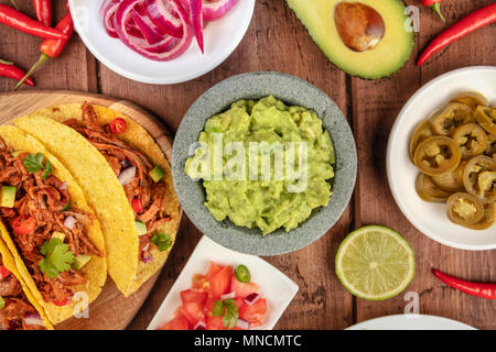 Ein Foto von einem ssortment vieler verschiedener mexikanische Lebensmittel, wie Tacos, Guacamole, Pico de Gallo, Jalapenos und andere Stockfoto