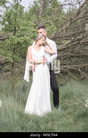 Schöne liebe Leute, Brautpaare, ein junges Paar, outdoor Session. Die Braut in einem weißen Kleid. Liebe, Hochzeit und Leidenschaft Stockfoto