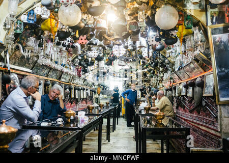Isfahan, Iran - Oktober 15, 2017: Männer sitzen und Tee an der Azadegan Teehaus, die berühmt für ihre riesige Sammlung von Bric-a-brac hängen von der Decke. Stockfoto