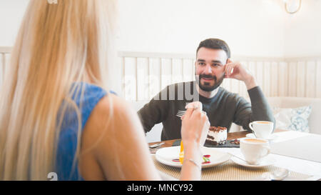 Stattlichen kaukasischen Mann vor der Frau zu sprechen, während sie Gespräch im Cafe Stockfoto