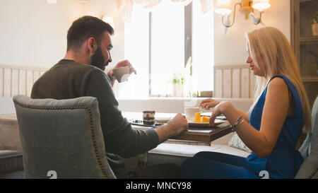 Glückliches Paar im Cafe genießen die Desserts und halten sich an den Händen Stockfoto