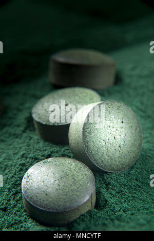 Nahaufnahme von Spirulina Tabletten auf Pulver Hintergrund mit geringer Tiefenschärfe. Bild vertikal. Stockfoto