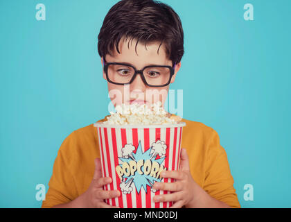 Kleiner Junge Kind mit Popcorn auf blauem Hintergrund Stockfoto