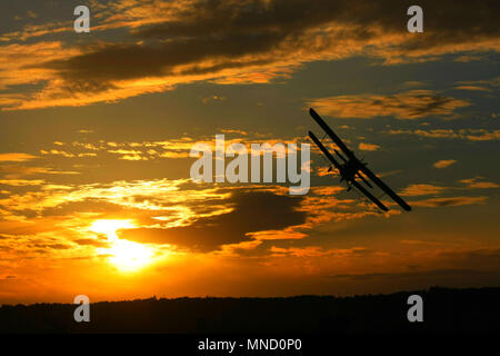 Eine schöne, magneficient Moment, wenn ein doppeldecker fliegen über den Himmel, während die Sonne hinter ihm geht. Stockfoto