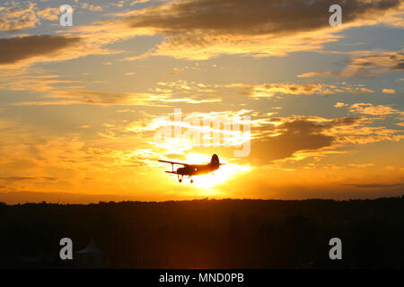 Ein doppeldecker fliegen über den Himmel, während die Sonne hinter sich. Sonnen Moment. Stockfoto