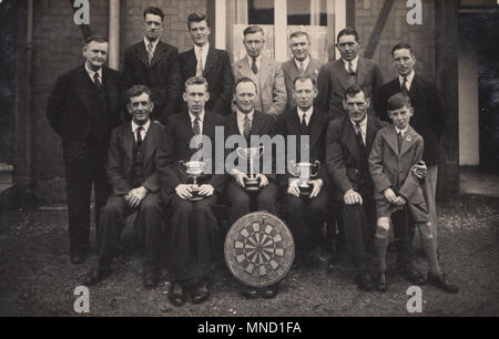 Vintage Foto einer öffentlichen Haus Dart Team mit ihren Trophäen und Dartboard Stockfoto