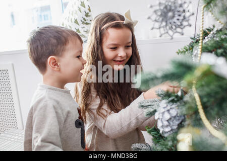 Gerne Geschwister schmücken Weihnachtsbaum zu Hause Stockfoto