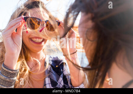 Zwei junge schöne Frau sehen sich mit Brillen in einem sonnigen Tag. Nettes lächeln gesehen von der Rückseite einer Frau. Freundschaft zwischen zwei spanischen Stockfoto