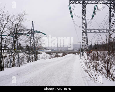 Hochspannungsleitung mit massiven Pylonen vorbei an einem verschneiten Fußweg am Stadtrand von Oslo Norwegen Stockfoto