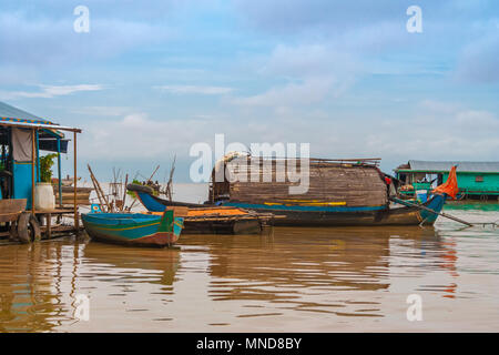 Eine hölzerne Sampan - wie Boot mit einem geschwungenen Dach gebunden bis zu einem schwimmenden Haus in Chong Kneas, die schwimmenden Dorf am Tonle Sap See in Kambodscha. Stockfoto