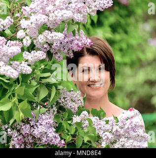 Lächelnde Frau in alilac Garten Stockfoto