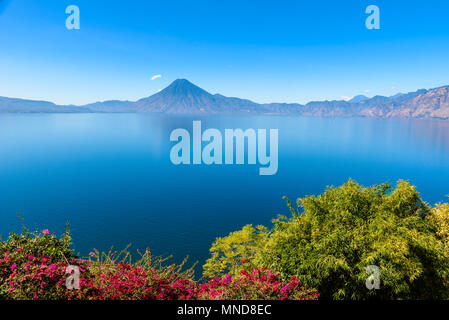 Blick von der Atitlan See am frühen Morgen, blauer Himmel, klares Wasser, wunderschöne magic See mit Vulkanen und indigene Bevölkerung im Hochland von Gu Stockfoto