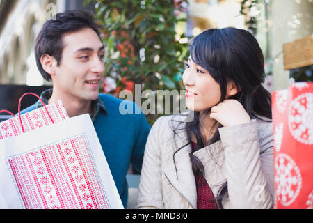 Liebevolle junge Paare mit Tüten sich einander im Freien Stockfoto