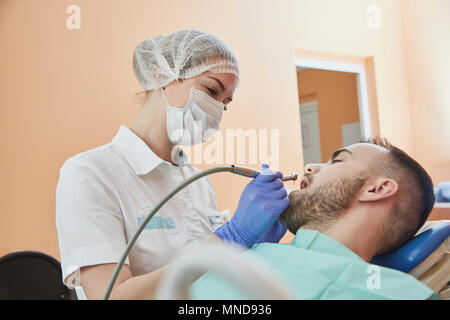 Zahnarzt das Tragen von Mundschutz und Kappe während der Prüfung männlicher Patient Stockfoto