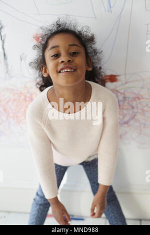 Porträt der lächelnde Mädchen stehend gegen Zeichnung an der Wand Stockfoto