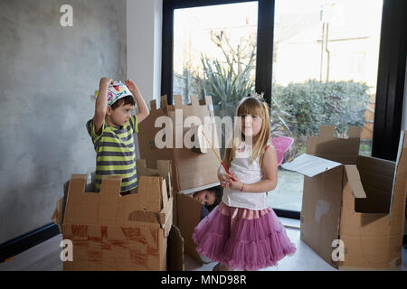 Kinder tragen Kostüm spielen mit Kartons gegen Fenster Stockfoto