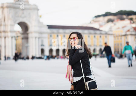 Seitenansicht der lächelnden Mitte der erwachsenen Frau am Town Square gegen Gebäude in der Stadt, Portugal Stockfoto