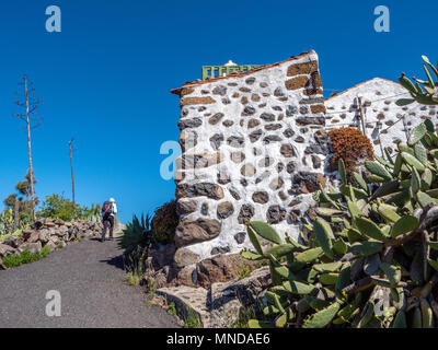 Ein Wanderer in der Nähe des Dorfes Chipude auf der Insel La Gomera auf den Kanarischen Inseln vorbei an einer weißen Mauern umgebenen Haus mit Opuntia Kakteen Stockfoto
