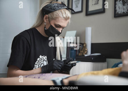 Tattoo artist Vorbereitung der Maschine während der Kunde im Studio sitzen Stockfoto