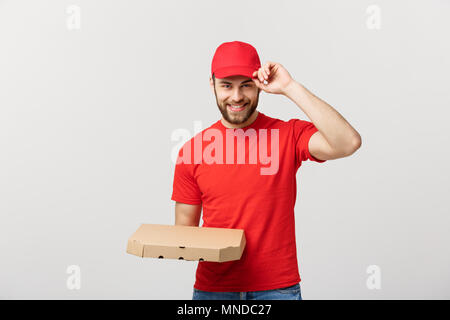 Lieferung Konzept: junge haapy kaukasischen stattlichen Pizza Delivery Man holding Pizzakartons über grauer Hintergrund Stockfoto