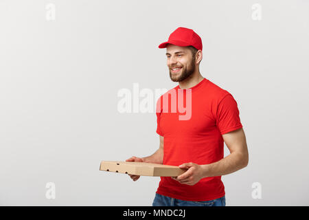 Lieferung Konzept: junge haapy kaukasischen stattlichen Pizza Delivery Man holding Pizzakartons über grauer Hintergrund Stockfoto