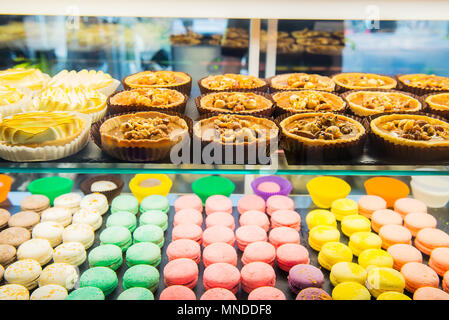 Sortiment Bunte macarons und Torten zum Verkauf im Shop. Raws von Süßigkeiten in Candy shop Storefront, Cafe präsentieren. Traditionelle französische Mandel Kuchen pa Stockfoto