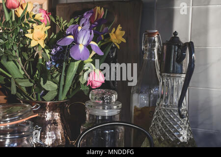 Die Zustellung der Blumen in stilvollen Küche, Großbritannien. Küche Dekoration, Stilleben Komposition, natürliches Sonnenlicht aus dem Fenster. Nachmittag Licht. Schnittblumen. Stockfoto