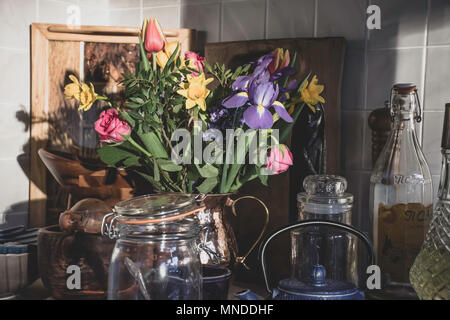 Die Zustellung der Blumen in stilvollen Küche, Großbritannien. Küche Dekoration Idee, noch Leben die Zusammensetzung, das natürliche Sonnenlicht aus dem Fenster. Nachmittag Licht. Design. Stockfoto