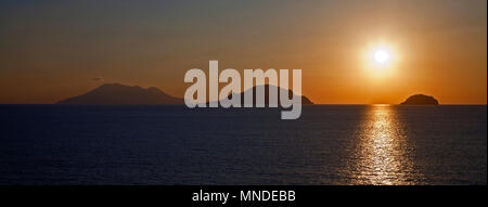 Ein helles Orange gelbe Sonne erstellen einen Schatten auf eine vulkanische Landschaft Stockfoto