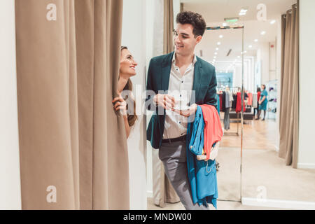 Mann in Fashion Store warten auf seine Frau aus dem Proberaum zu erscheinen Stockfoto