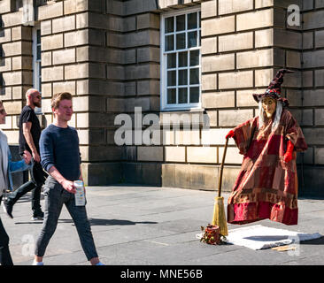 Royal Mile, Edinburgh, 16. Mai 2018. Touristen genießen die Sonne und die Straßenunterhaltung auf der Royal Mile, Edinburgh, Schottland, Vereinigtes Königreich. Menschen vorbei an einer frei schwebenden lebende Statue Street Performer als Hexe verkleidet Stockfoto