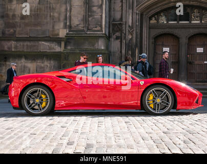 Royal Mile, Edinburgh, Schottland, Vereinigtes Königreich, Mai 2018. Leute, die von einem hellen roten Ferrari 488 GTB coupé Sportwagen auf einer doppelten gelben Linie auf dem gepflasterten Royal Mile geparkt neben der St. Giles Cathedral, die neidvolle Blicke Stockfoto