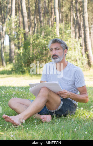 gut aussehender Mann malen eine Frühlingslandschaft Stockfoto