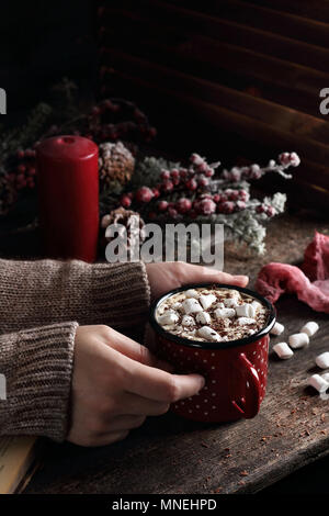 Becher mit heißem Kaffee mit Marshmallow und Schokolade in Frau Hände, Weihnachtsschmuck Stockfoto