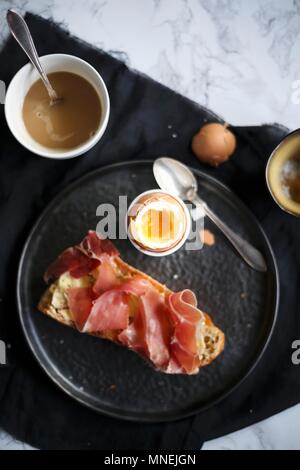 Frühstück mit einem weich gekochten Ei und Brot mit Schinken Stockfoto