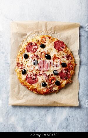 Rustikale Pizza mit würzigen Salami, Käse und red chili peppers Stockfoto