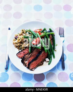 Gegrillte butterflied Lammkeule mit grünen Bohnen feta Salat und gerösteten Orzo Stockfoto