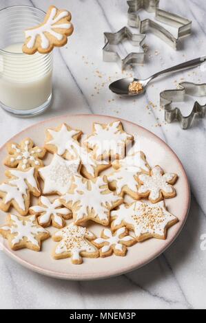 Glasierte butter Cookies, ein Glas Milch und verschiedene Ausstechformen Stockfoto