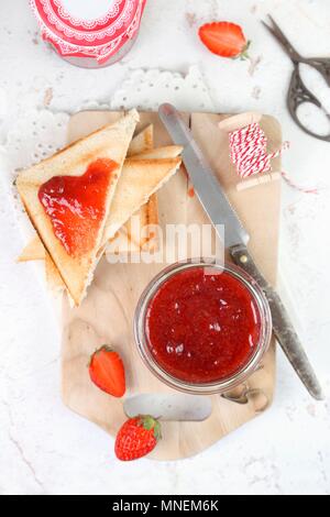 Hausgemachte Erdbeermarmelade in einem Glas und auf Dreiecken toast Stockfoto