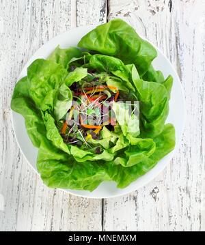 Salat auf einem weißen Teller; auf einen hölzernen Tisch; von oben Stockfoto